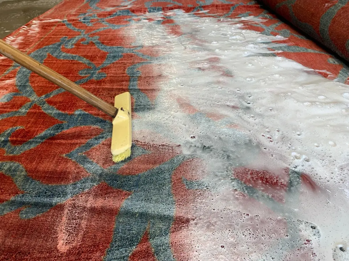 Lavage à la brosse d’un tapis rouge dans l’atelier